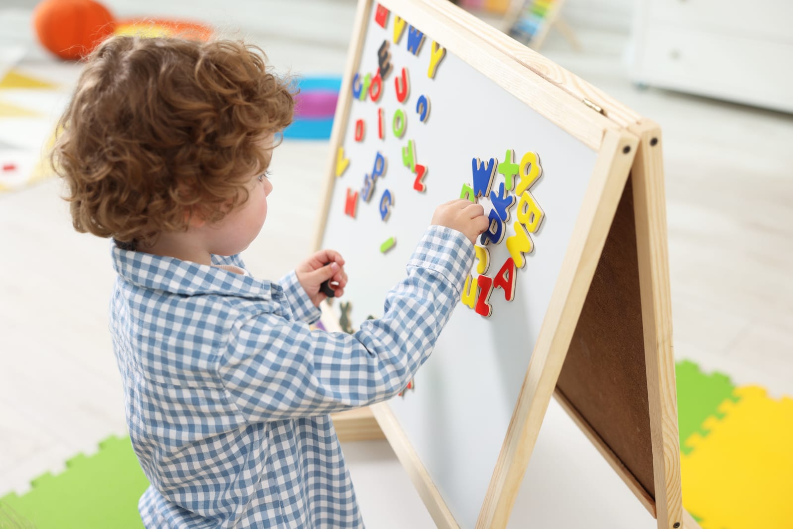 Criança brinca com letras magnéticas em um quadro